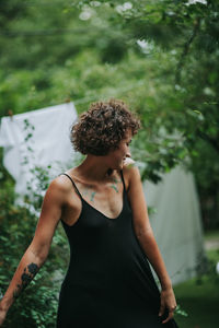 Young woman standing against plants