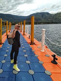 Full length of woman standing on pier in lake