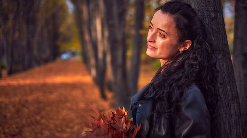 Young woman looking at tree trunk during autumn