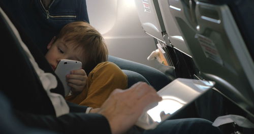 Rear view of man using mobile phone while sitting in bus