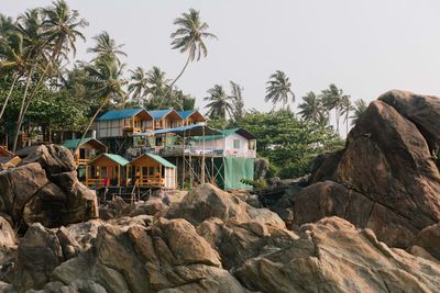 Rock formation amidst trees and houses against clear sky