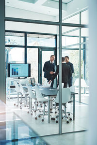 Rear view of man standing with colleagues in office