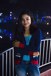 Portrait of smiling young woman standing at night