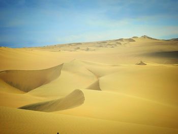 Sand dunes in desert against sky