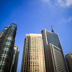 Low angle view of modern buildings against blue sky