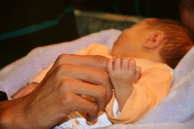 Newborn baby holding cropped hand of man