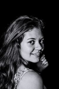 Portrait of smiling young woman against black background