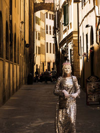 Portrait of woman standing on street amidst buildings in city