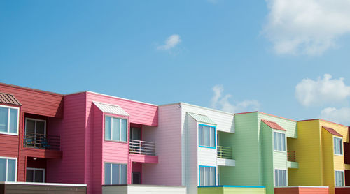 Low angle view of multi colored buildings against blue sky