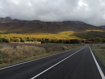 Empty road along landscape against sky