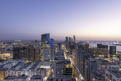 High angle view of illuminated city buildings against clear sky