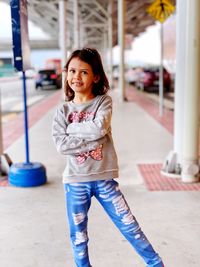 Portrait of smiling girl standing on footpath