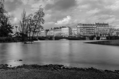 Scenic view of river by buildings against sky