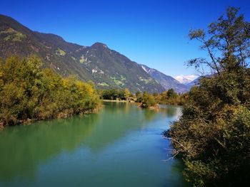 Scenic view of lake and mountains against blue sky