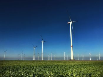 Windmills on field against sky