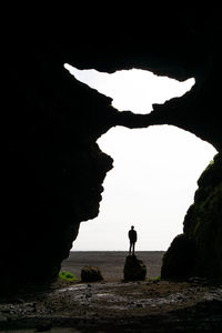 Silhouette man standing on rock formation against sky