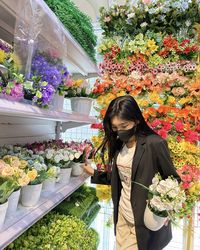 Portrait of young woman standing amidst flowers
