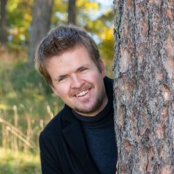 Portrait of smiling young man by tree trunk