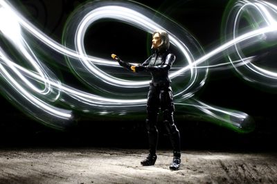Blurred motion of person standing at illuminated light trails at night