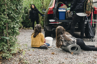 Family loading luggage in electric car trunk