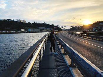 Man on bridge over city against sky during sunset