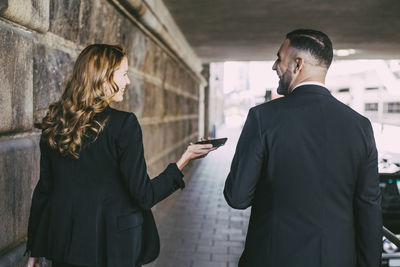 Rear view of businesswoman talking to businessman in city