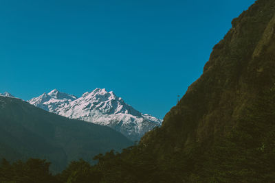 Scenic view of snowcapped mountains against clear blue sky