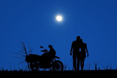 Silhouette people riding bicycles against clear blue sky