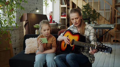 Mother teaching guitar to daughter