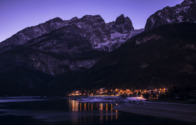 Scenic view of lake by mountains against sky at night