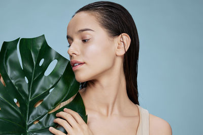 Close-up of young woman against blue background