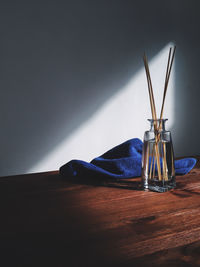 Sticks in vase by towel on hardwood floor