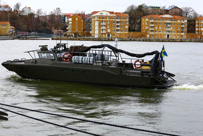 Boat moored on river by buildings in city