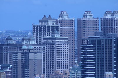 Buildings in city against clear blue sky