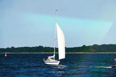 Sailboat sailing on sea against sky