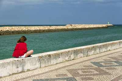 Rear view of woman overlooking calm blue sea