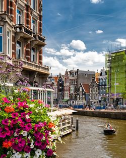 Canal amidst buildings in city against sky