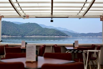 Empty chairs and tables at restaurant against sea