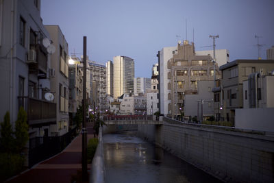 Canal amidst buildings against sky at dusk