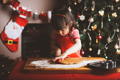 Girl making cookies at table during christmas