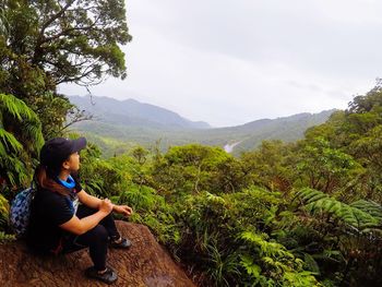 Full length of view sitting on rock against forest