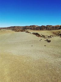 Scenic view of sand dunes against clear blue sky