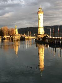 View of lighthouse by buildings against sky