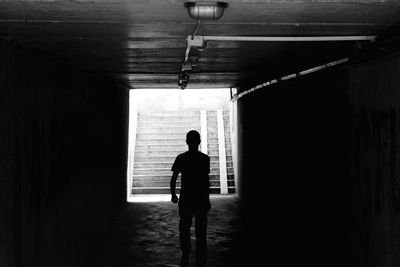 Silhouette man walking in underground walkway