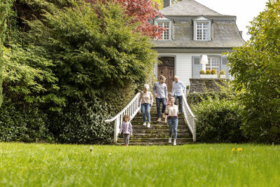 Extended family walking on stairs in garden of their home