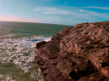 Rock formations by sea against sky