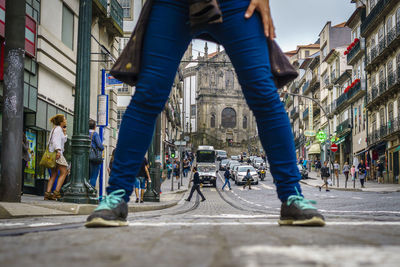 Low section of people walking on street amidst buildings in city