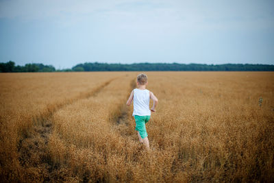 Rear view of man standing on field against sky