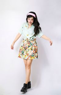 Portrait of young woman standing against white background