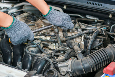 The mechanic is tightening the nut in the engine compartment of the car.